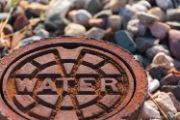 Manhole cover stamped with "WATER", in a rocky area