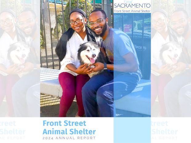  two people and a dog sitting on the bench in front of the shelter