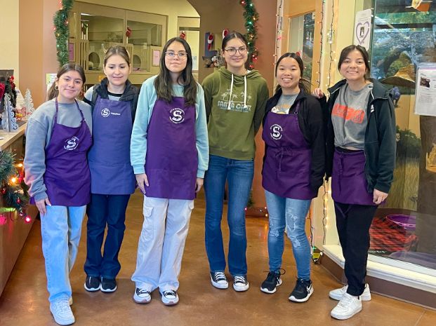 group of volunteers wearing a purple apron and standing inside the cattery building