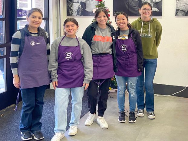 volunteers wearing a purple apron and standing inside the office lobby