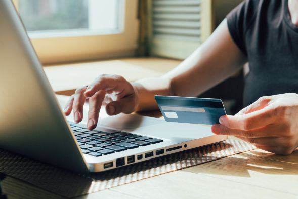 Person holding a payment card near a computer