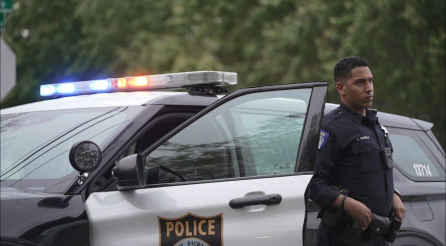 Sacramento Police officer standing in front of police vehicle