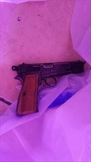 A photo of the suspect's black handgun with wooden paneling along the handle, which was recovered from the scene
