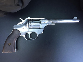 A photo of a silver revolver with a brown handle,  which officers located in the immediate proximity of the suspect