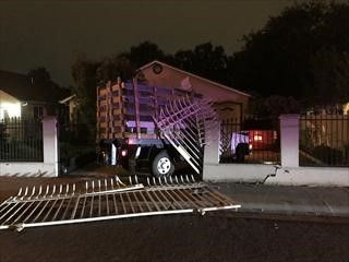 A photo of the suspect's truck crashed through a neighboring home's front fence, with part of the the police station's damaged fence laying the street in front of the house
