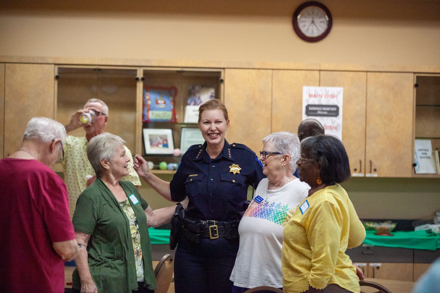 A photo of uniformed Sacramento Police Chief Kathy Lester laughing with a small group of  community members at a community center during National night out