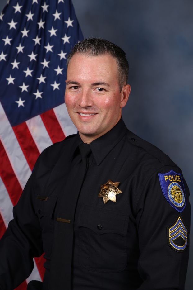 Photo of Chad Coughran in uniform standing in front of the American flag.