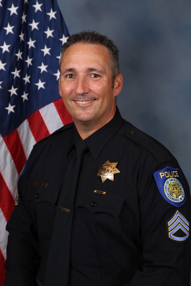 Photo of Michael Rinehart in uniform standing in front of the American flag.