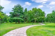 Stock image of outdoor park setting with trees, grass, and paver walkway path