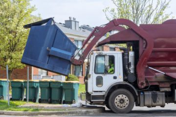 Trash truck lifting big blue bin