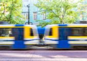 Photo of SacRT trains in motion on a tree-lined street